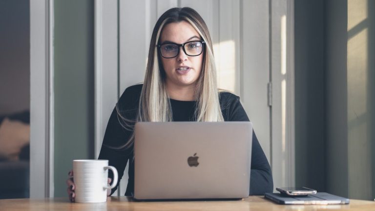 woman in black framed eyeglasses using macbook