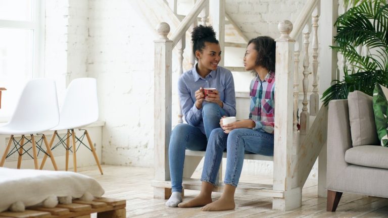 Two young women talking on stairs with coffee