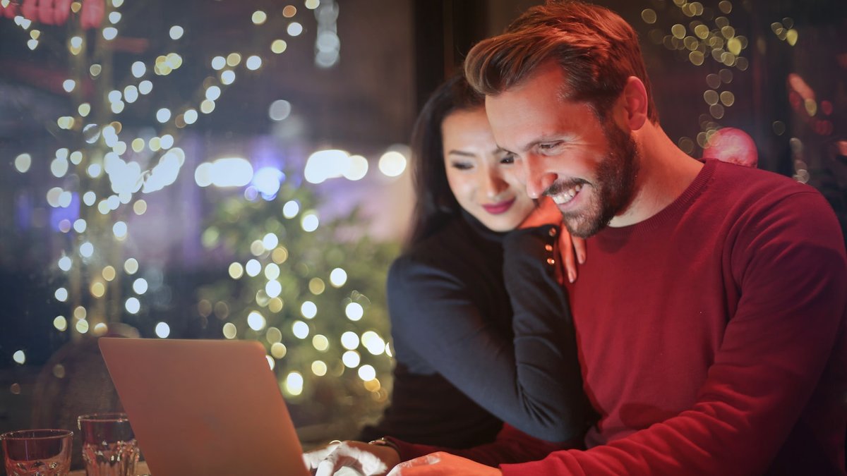 man and woman looking on silver laptop while smiling