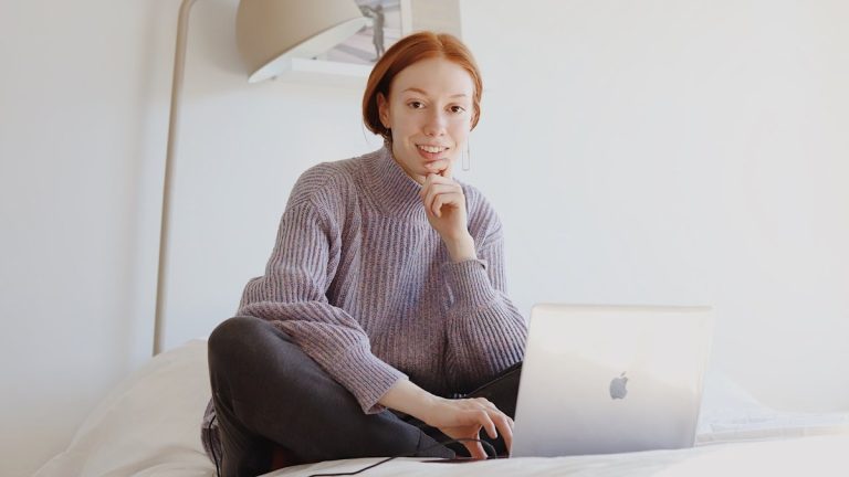 woman in gray sweater sitting on chair using macbook