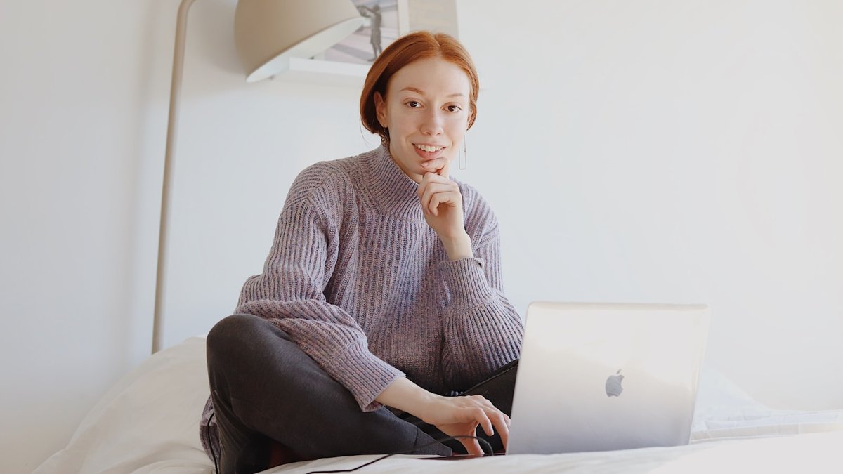 woman in gray sweater sitting on chair using macbook