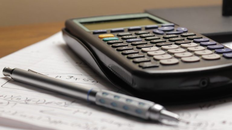 a calculator and a pen sitting on top of a piece of paper